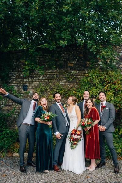 Bride bridesmaids pose for a picture in garden with groom and groomsmen