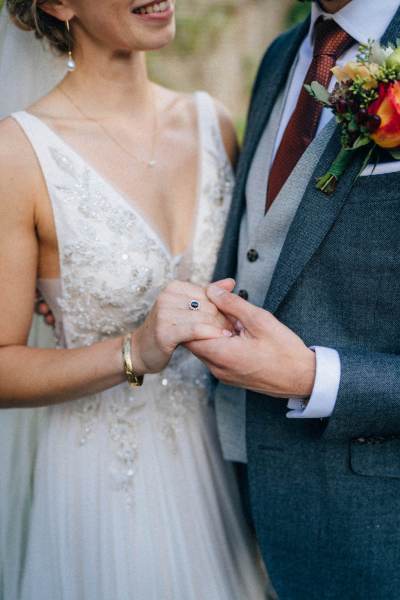 Bride and groom touch foreheads holding hands hand in hand in garden