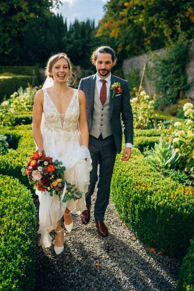 Bride and groom walk along pathway in garden