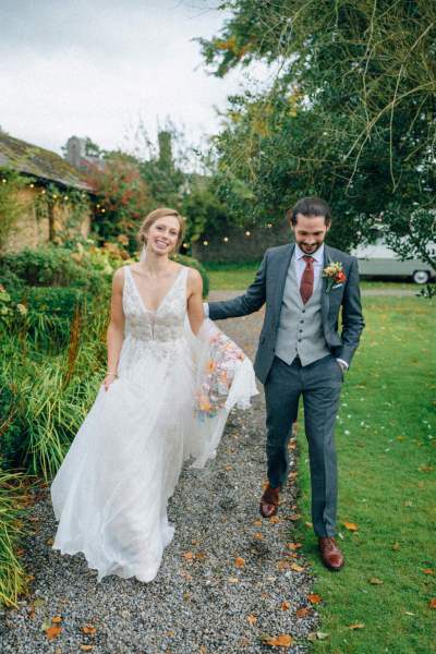 Bride and groom walk along pathway in garden