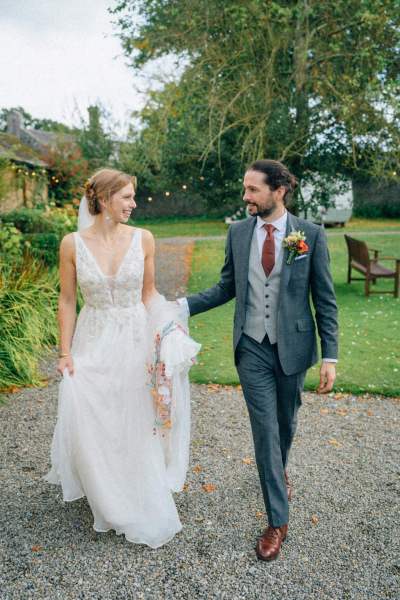 Bride and groom walk along pathway in garden