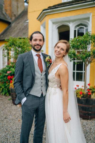 Bride and groom pose for a picture outside of wedding venue