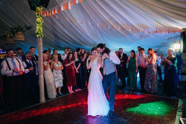 Bride and groom dancing on the dancefloor surrounded by guests