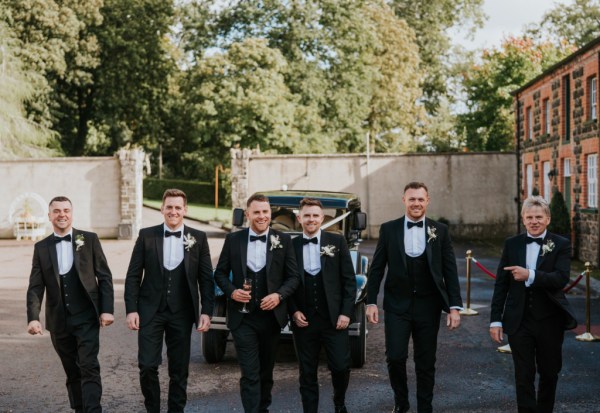 Groom best man and groomsmen in front of wedding car