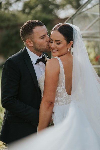 Bride and groom kiss on the cheek