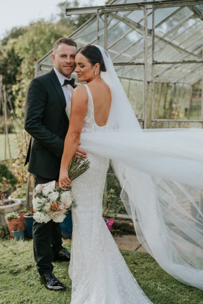 Bride and groom veil blowing in the wind holding bouquet