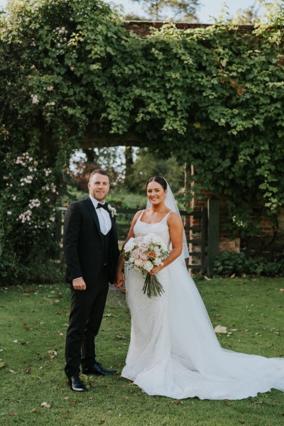 Bride and groom stand in garden together