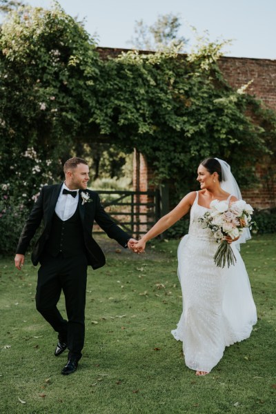 Bride and groom walk on the grass in garden exterior shot