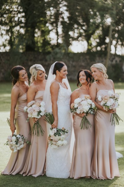 Bride and bridesmaids exterior shot in garden with bouquet of flowers