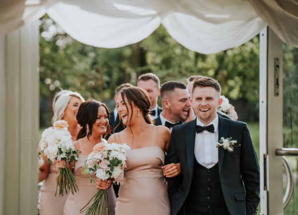 Bridesmaids smile holding flowers