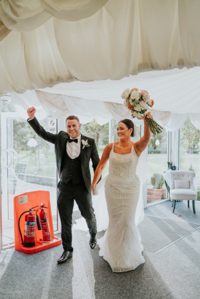 Bride and groom enter ballroom carrying bouquet flowers roses