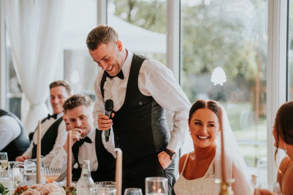 Groom during his speech bride laughing at table