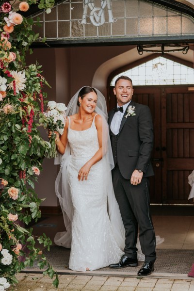 Bride and groom standing beside flowers bed exterior church setting