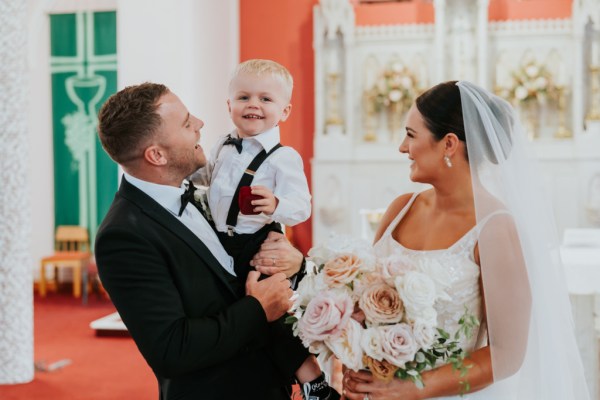 Bride groom and son smiling for the camera pink roses