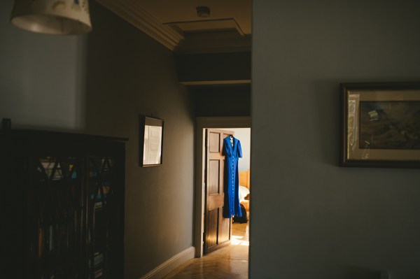 Blue bridesmaid dress hangs up at door