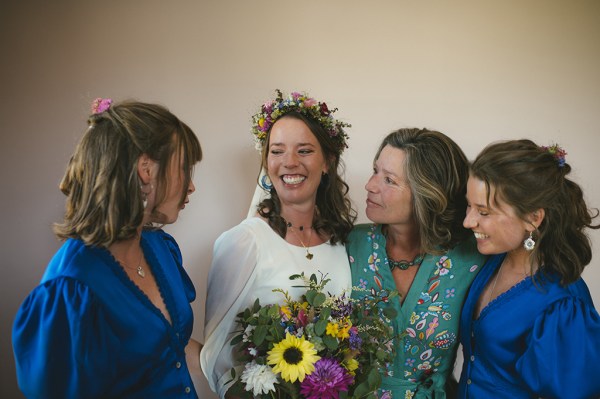 Mother bridesmaids and bride holding flowers smile together