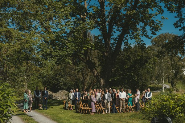 Guests stand as bridesmaids and bride head to wedding ceremony