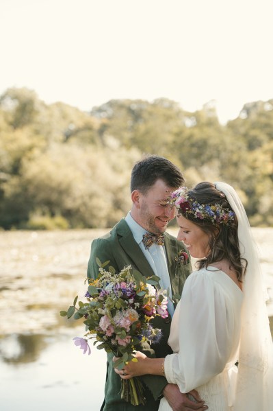 Bride holding bouquet of flowers laughing with groom