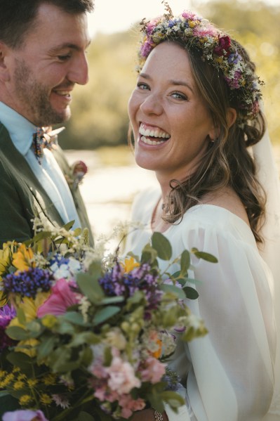 Bride holding bouquet of flowers laughing with groom