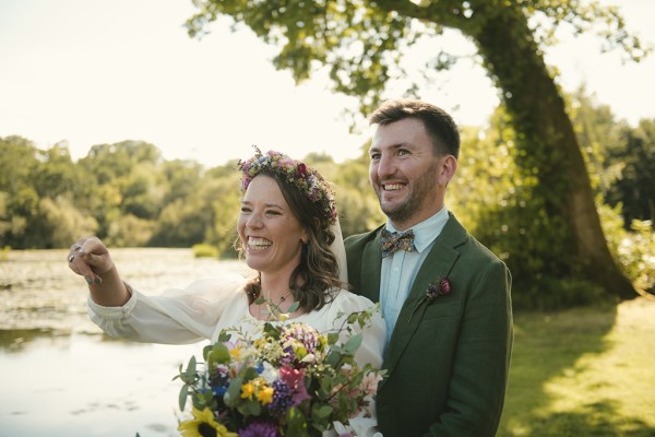 Bride and groom pose in the park/garden flowers/bouquet in shot