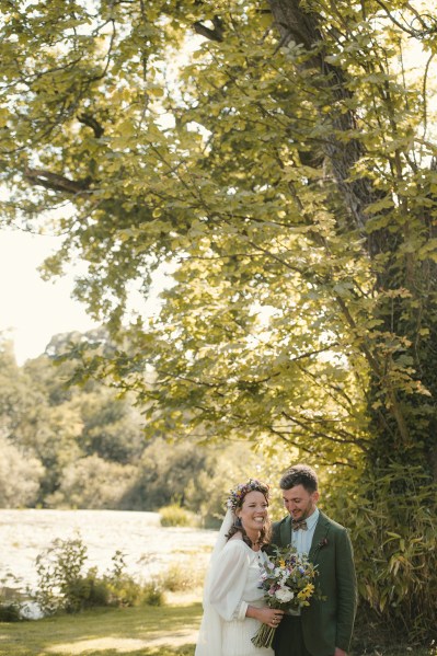 Bride holding bouquet of flowers laughing with groom