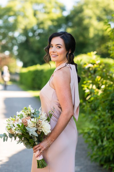 Bridesmaid standing holding bouquet of flowers in garden