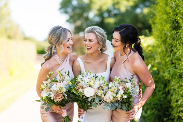 Bride and bridesmaids lauging park setting