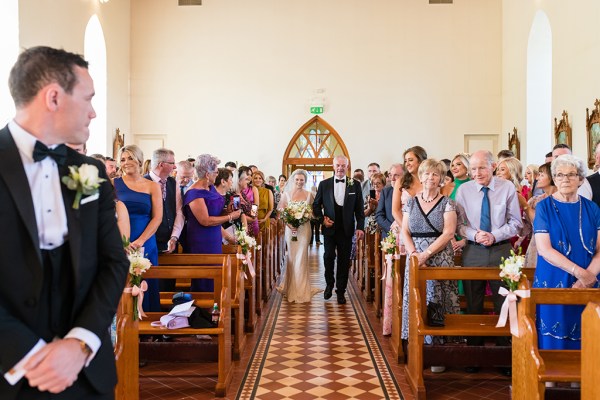 Interior church setting father of the bride walking down the aisle