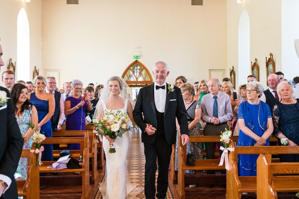 Interior church setting father of the bride walking down the aisle