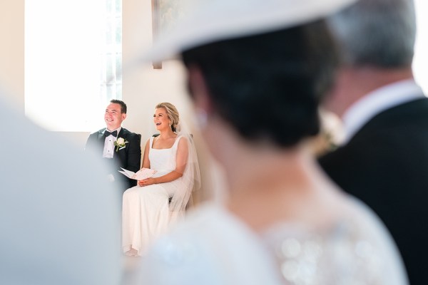 Bride and groom sitting down church interior guests