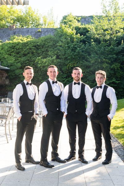 Groom and groomsmen standing exterior wedding venue