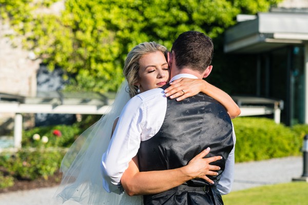 Bride and groom embrace in the sun exterior setting park