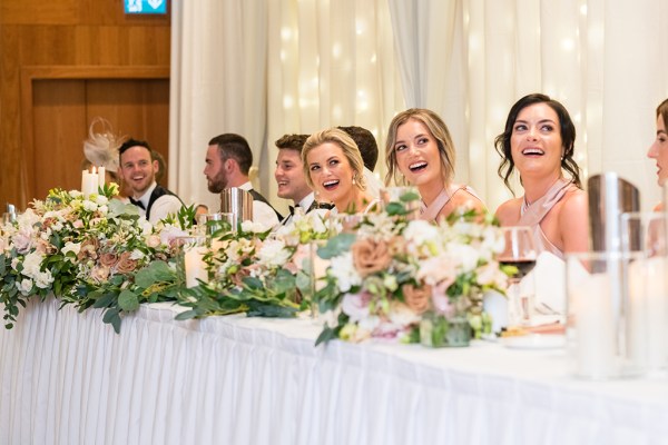 Bridesmaids laugh during speech at table