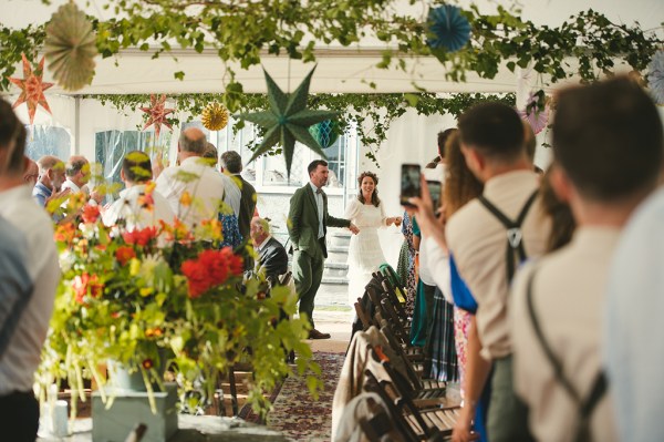 Bride and groom enter marquee setting with guests clapping