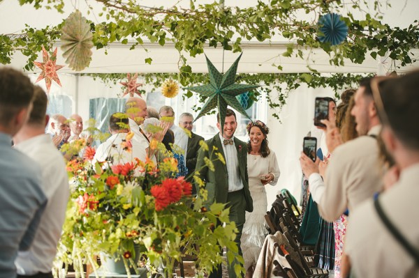 Bride and groom enter marquee setting with guests clapping