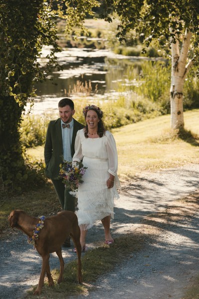 Bride groom and dog walk on the grass in park