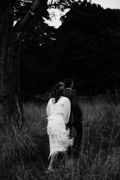 Bride and groom walk through garden black and white photography