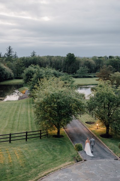 Drone footage shot of bride and groom hand in hand on pathway