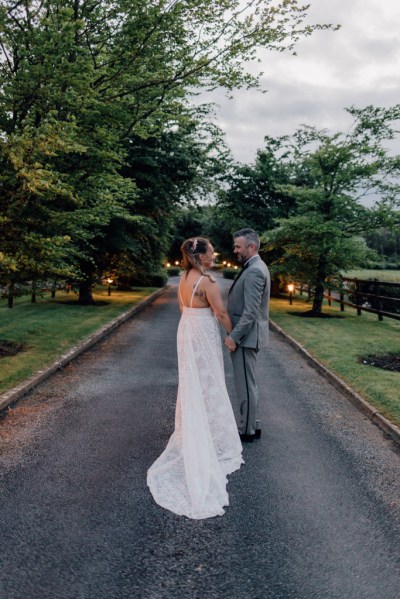 Bride and groom standing on pathway holding hands