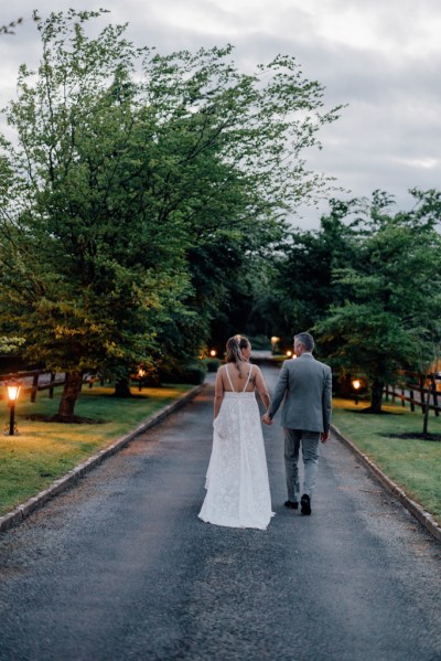 Bride and groom from behind walking hand in hand on pathway