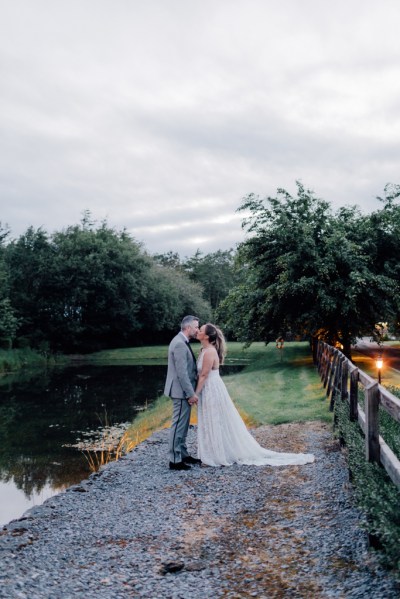 image of couple lake in background kissing kiss on grass