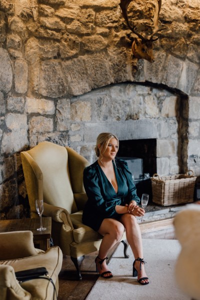 Bridesmaids sits beside fireplace in bridalwear