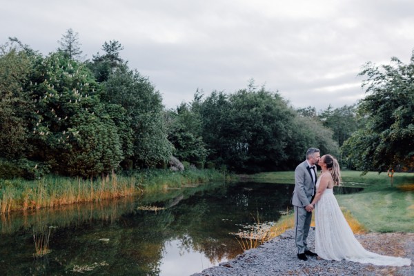 image of couple lake in background kissing kiss on grass