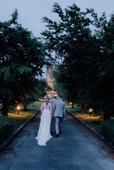 Bride and groom walk down pathway evening shot