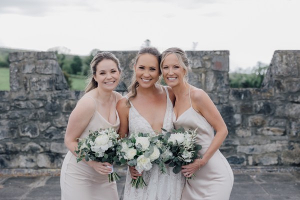 Bridesmaids and bride holding bouquet exterior castle wedding venue