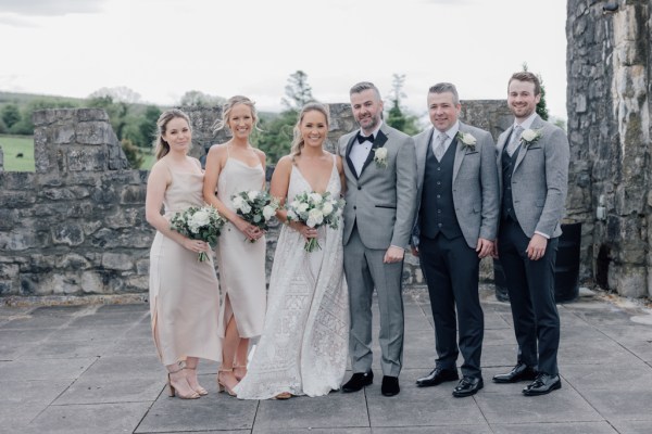 Bridesmaids and groomsmen either side of couple bride and groom pose for a photo