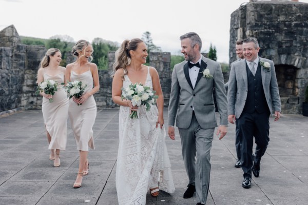 Bridesmaids and groomsmen either side of couple bride and groom looking at each other walking