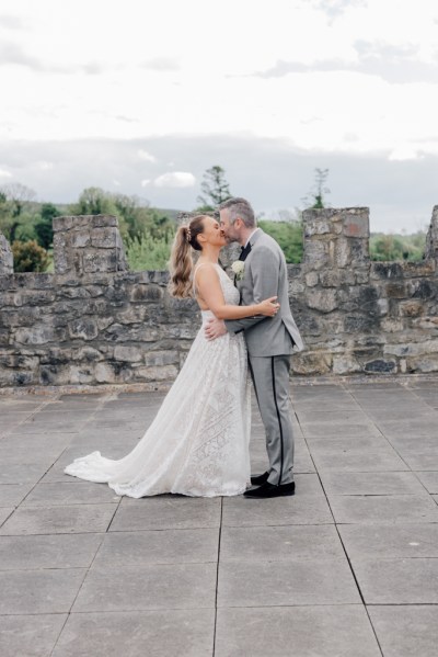 Bride and groom castle exterior rooftop kissing hugging kiss