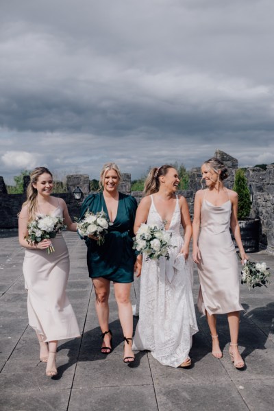 Bridesmaids and bride exterior shot walk together