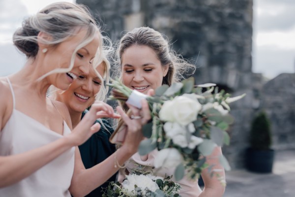 Bridesmaids and friends smile together looking at phone